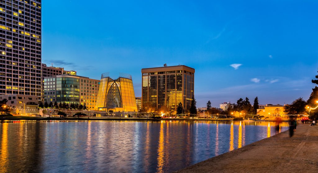 Oakland, California. Evening view across Lake Merritt with beautiful reflections of buildings and lights on the water. The "Necklace of Lights" illuminates the pedestrian walk around the lake. Copy space.